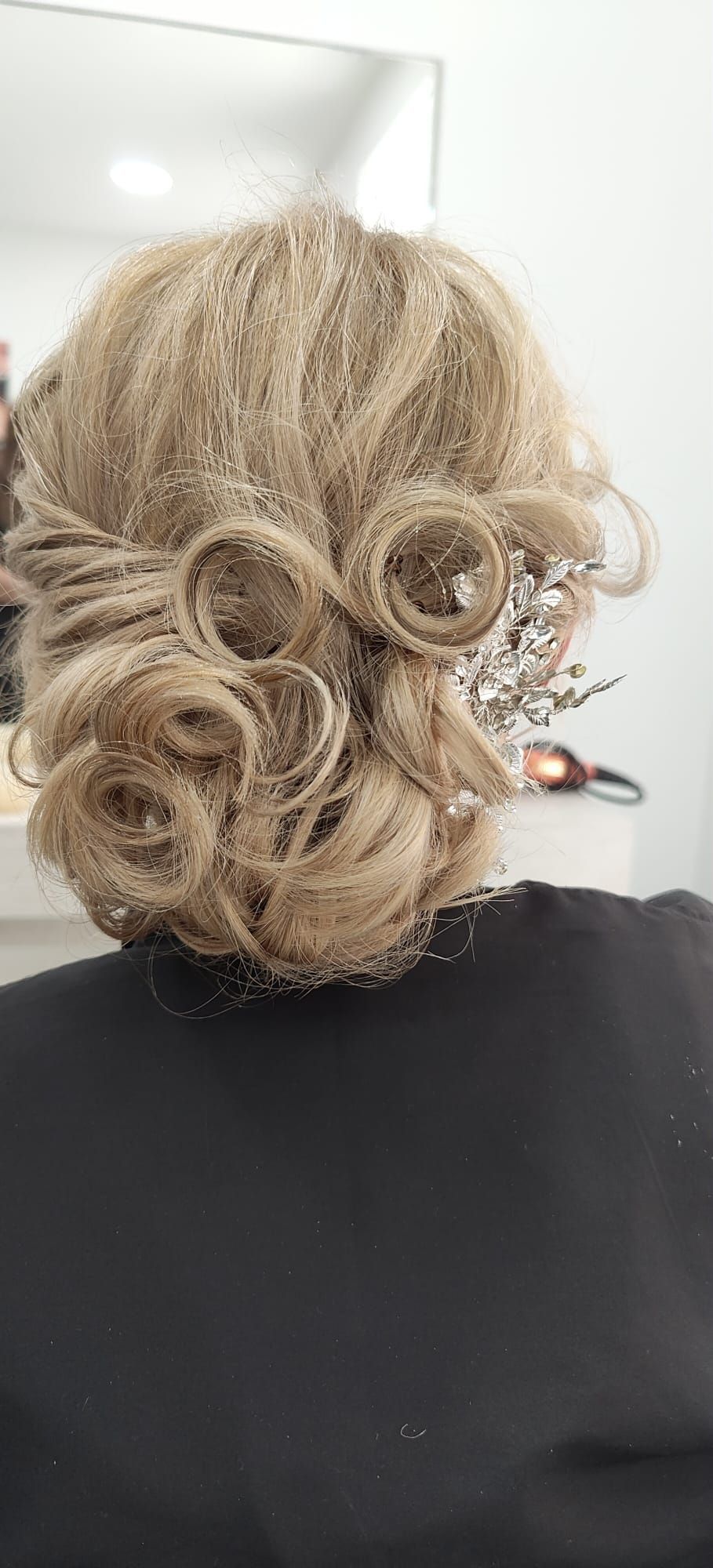 La parte posterior de la cabeza de una mujer con un moño y una flor en el pelo.