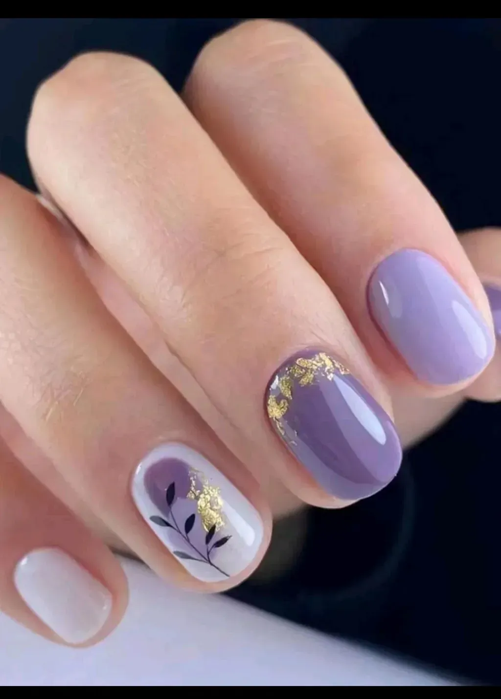 Un primer plano de las uñas de una mujer con un diseño morado y blanco.