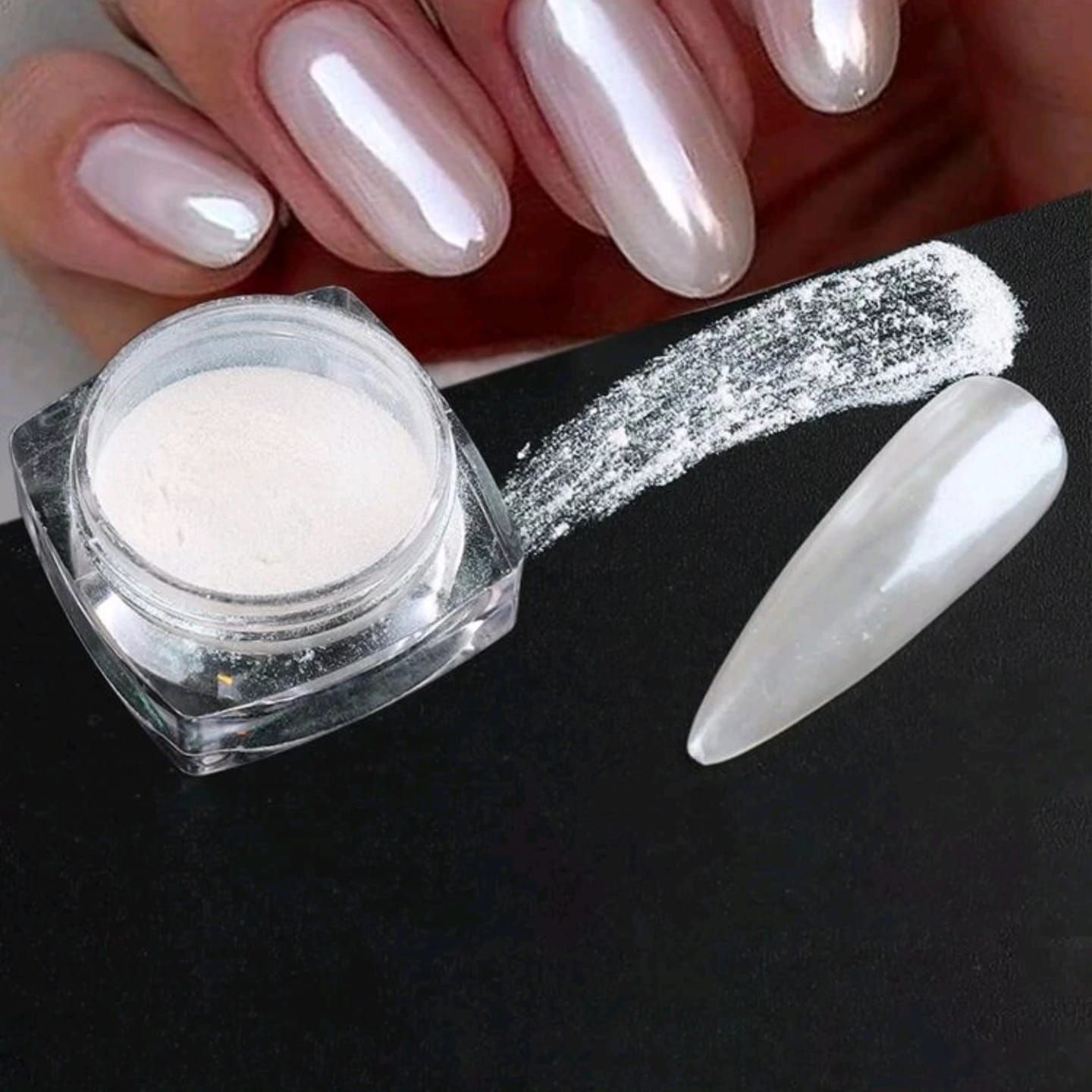 Se muestran las uñas de una mujer junto a un frasco de polvo de perla.