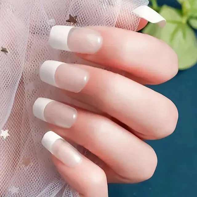 Un primer plano de las uñas de una mujer con una manicura francesa blanca.