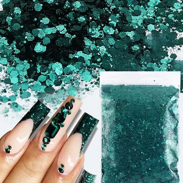 Las uñas de una mujer están decoradas con brillantina verde y diamantes de imitación.