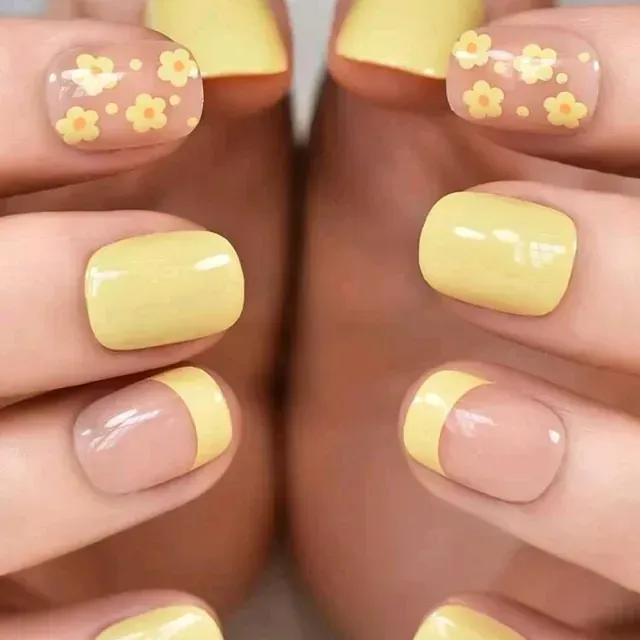 Un primer plano de las uñas de una mujer con flores amarillas en ellas.
