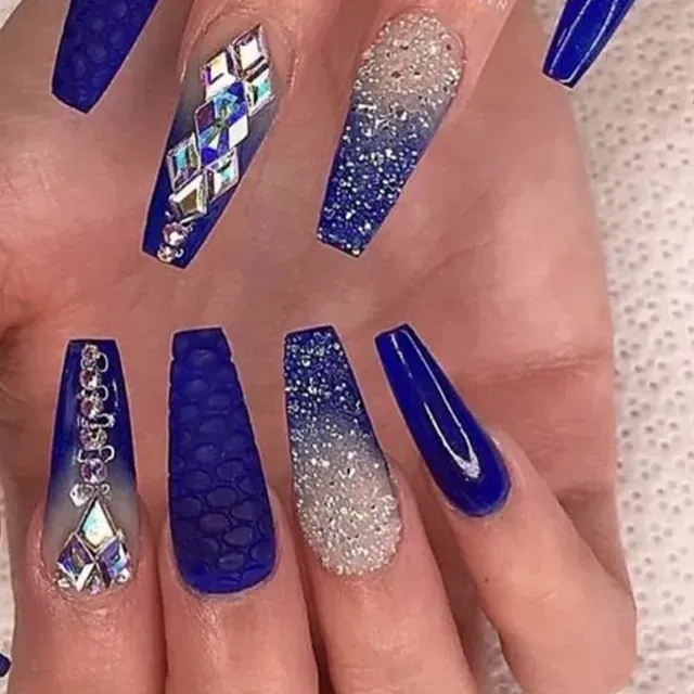 Un primer plano de la mano de una mujer con largas uñas azules y diamantes de imitación.