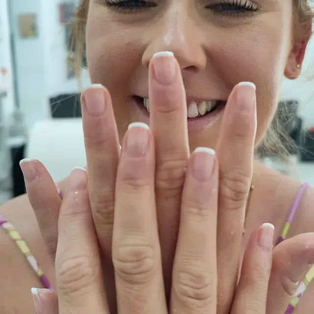 Un primer plano de las manos de una mujer con manicura francesa.