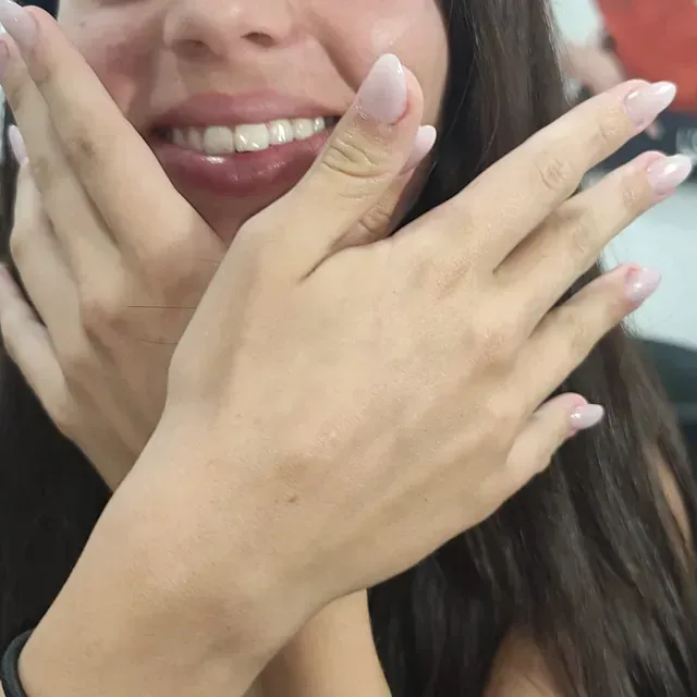 Una mujer cubriéndose la cara con las manos y sonriendo