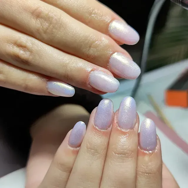 Un primer plano de las manos de una mujer con uñas moradas.