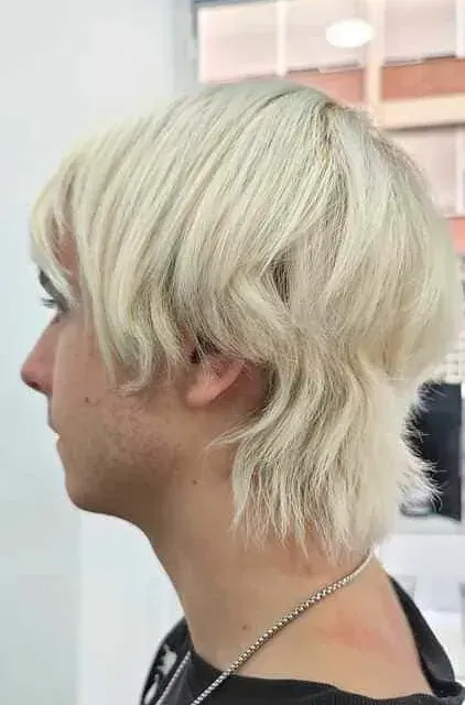 Un hombre con cabello rubio lleva una camisa negra y un collar.