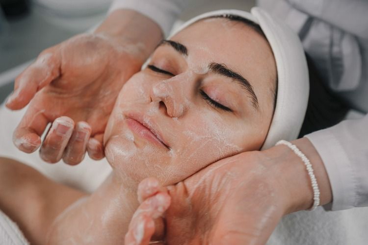 Una mujer está recibiendo un masaje facial en un spa.