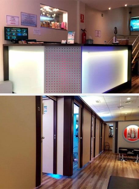 Moderna zona de recepción con mostrador iluminado y pasillo con suelo de madera y puertas