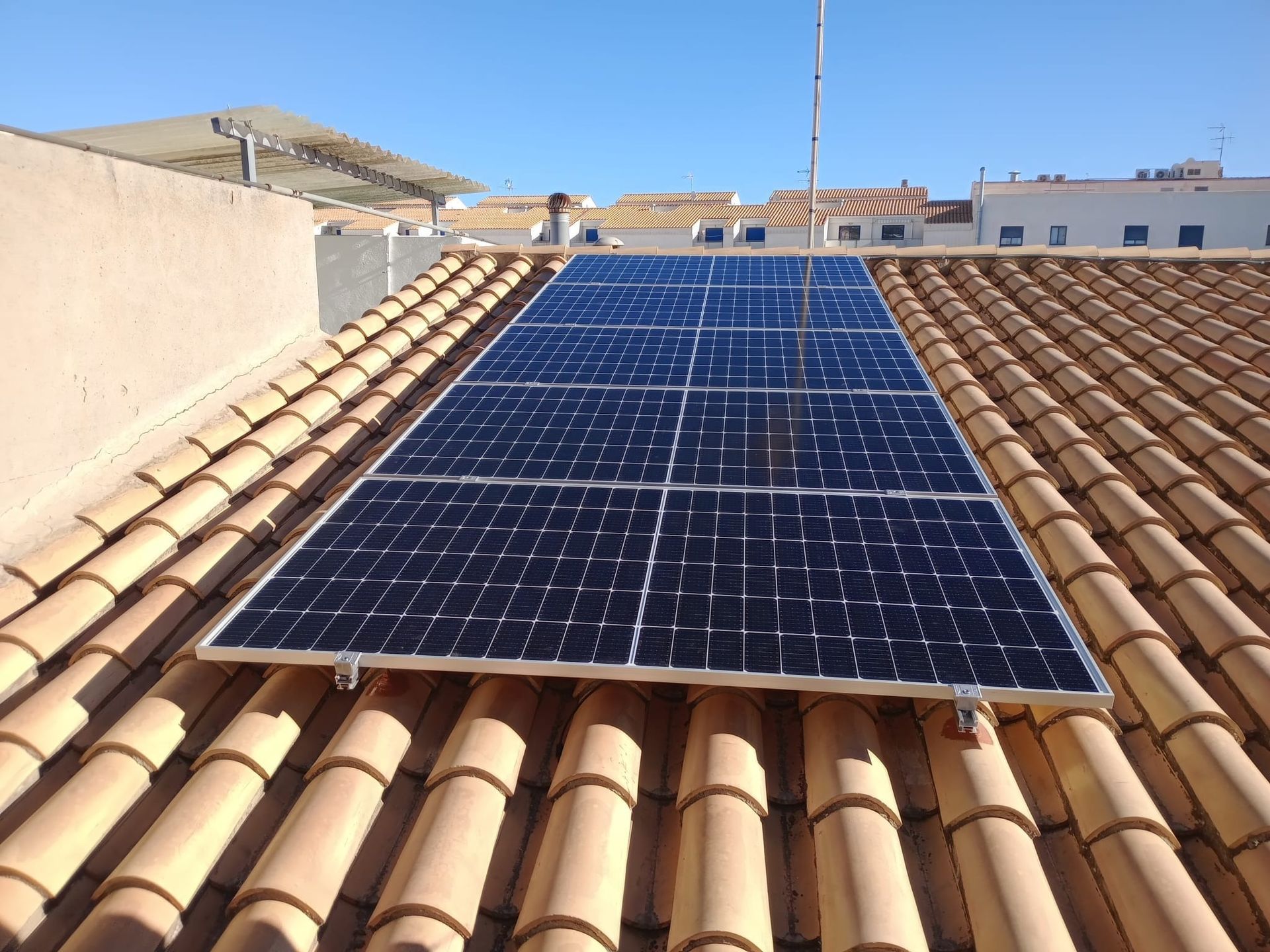 Paneles solares instalados en un techo de tejas en un entorno soleado.