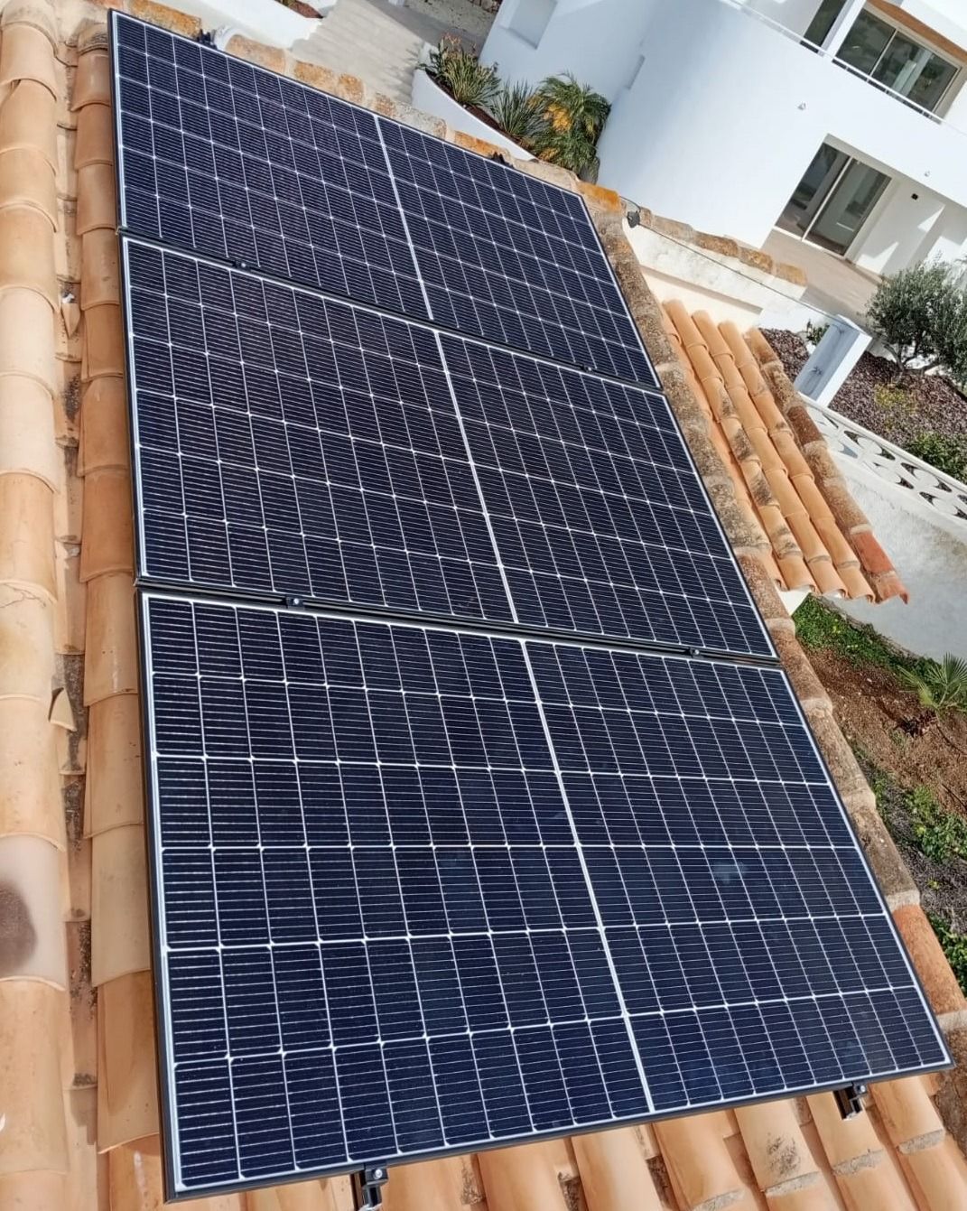 Paneles solares instalados en un techo de tejas de terracota, captando la luz solar para obtener energía.