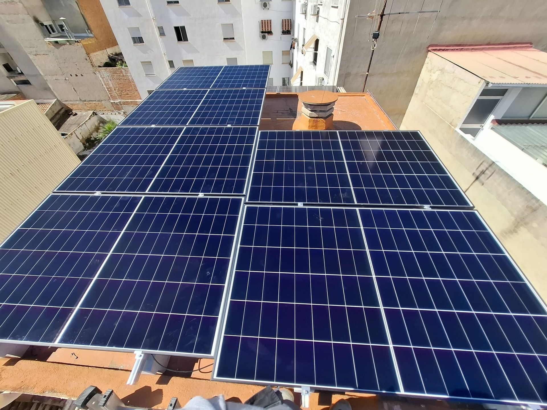 Paneles solares instalados en un tejado con edificios circundantes visibles.
