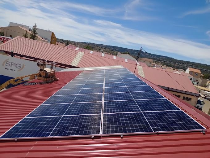 Paneles solares instalados en un tejado rojo inclinado bajo un cielo azul.