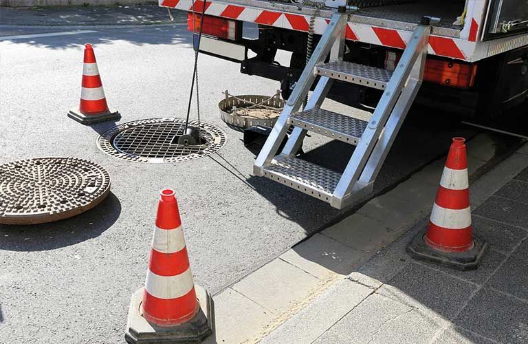 Ein LKW steht am Straßenrand neben einem Gullydeckel.