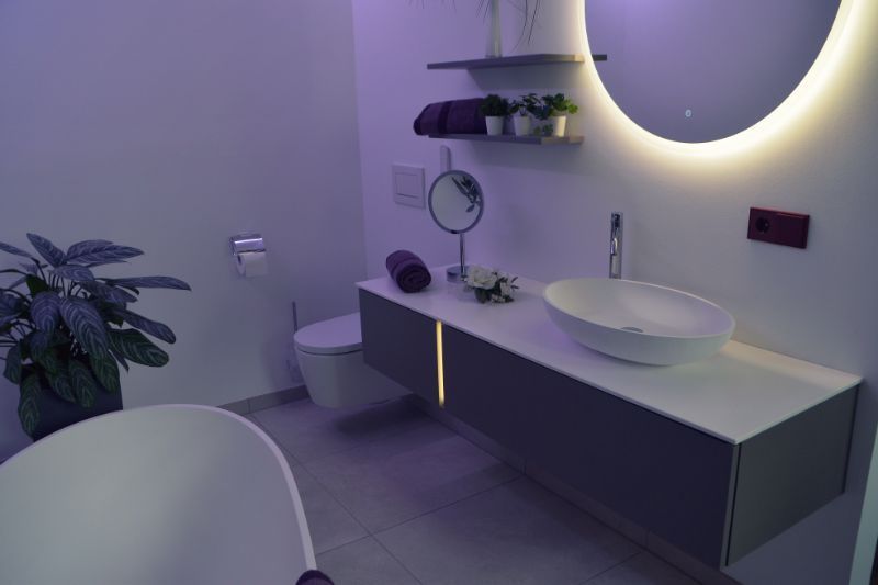 Badezimmer mit Badewanne und beleuchtetem Spiegel über dem Waschbecken