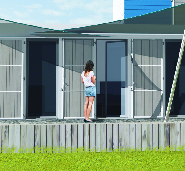 Une femme se tient debout sur une terrasse en bois devant un bâtiment moderne aux portes ouvertes