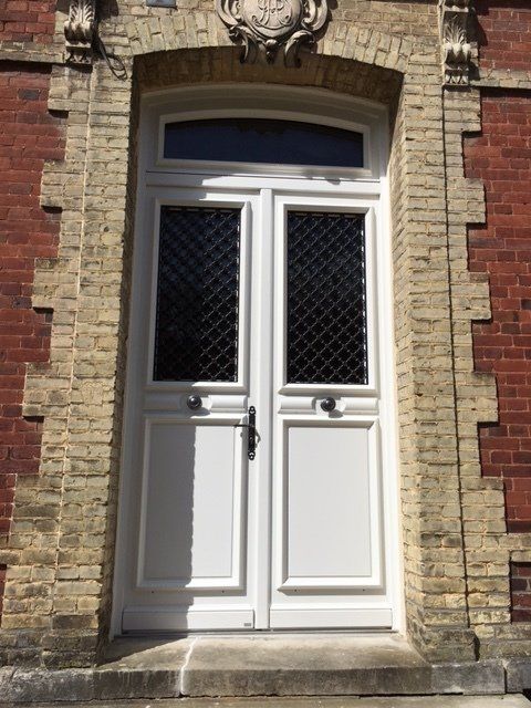 Double porte blanche avec encadrement en verre et en briques.
