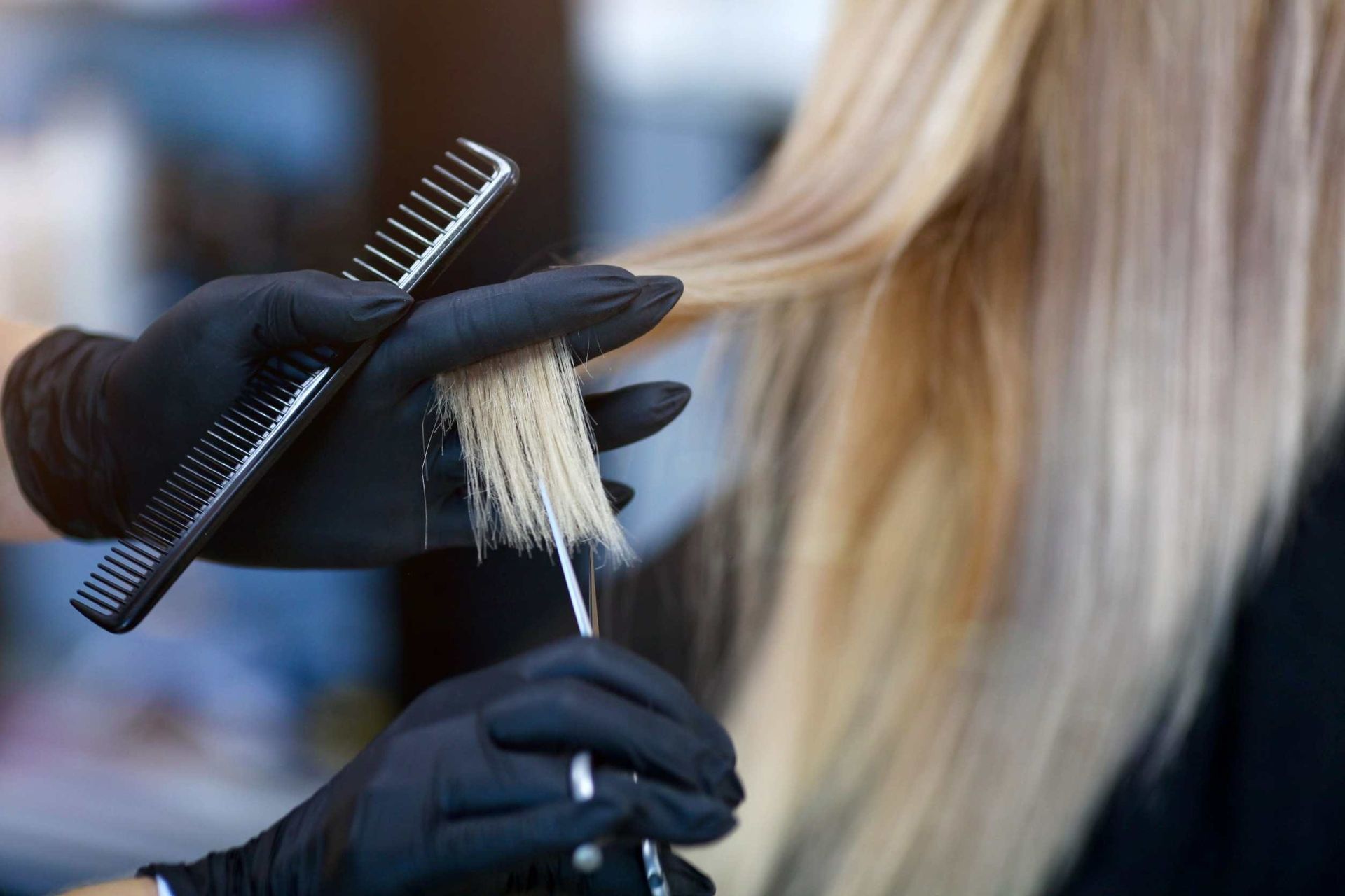 Peluquera cortando cabello rubio con tijeras y peine.