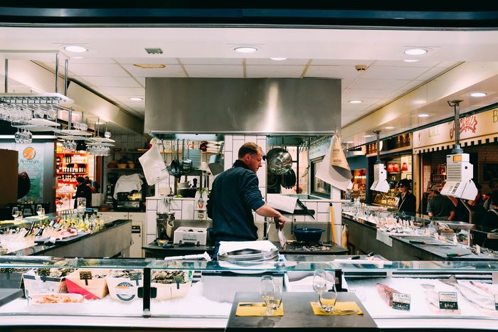 Cuisine professionnelle animée avec un chef travaillant à un comptoir en acier inoxydable sous une lumière vive