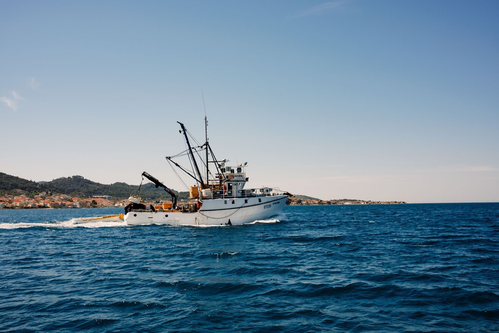 Bateau de pêche sur une mer bleue près d'une côte rocheuse sous un ciel dégagé