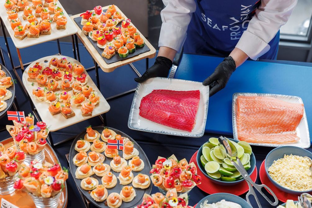 Buffet de sushis avec plateaux de nigaris colorés, sashimis et quartiers de citron vert et un serveur ganté préparant les plats.