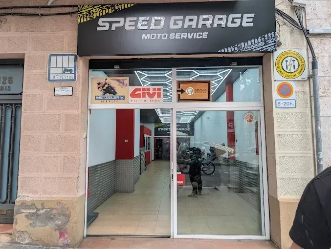 Fachada del taller mecánico Speed ​​Garage con entrada de cristal y scooter en el interior.