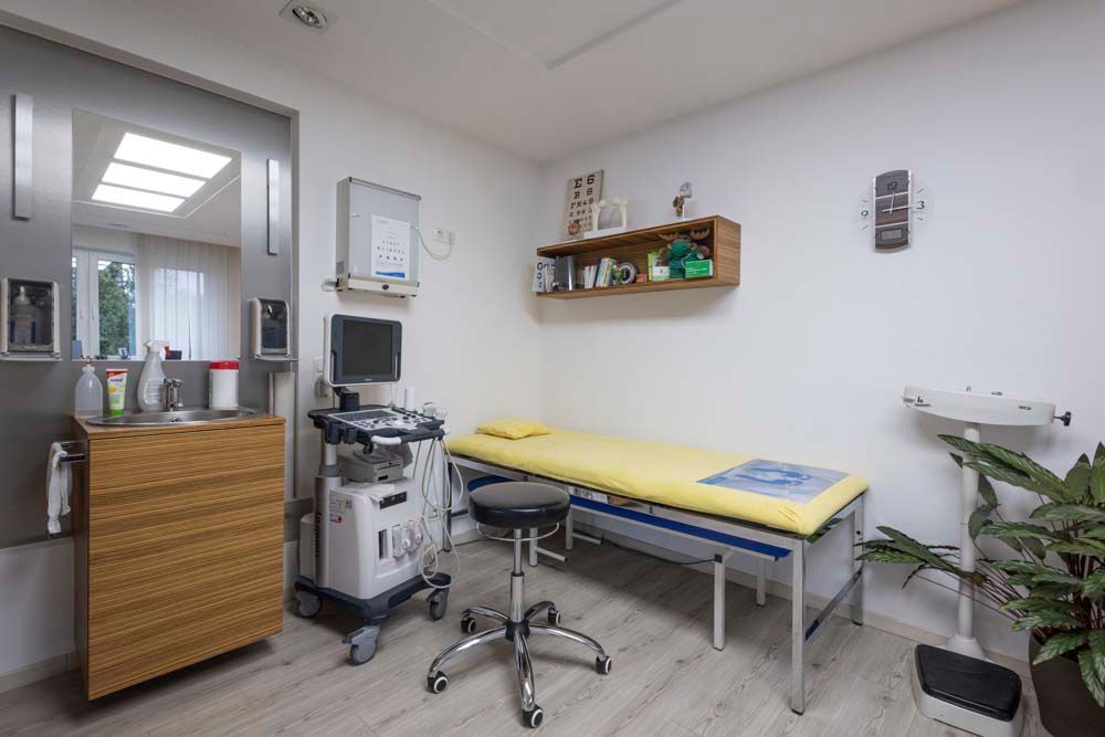 Eine Arztpraxis mit Bett, Stuhl und Ultraschallgerät.
