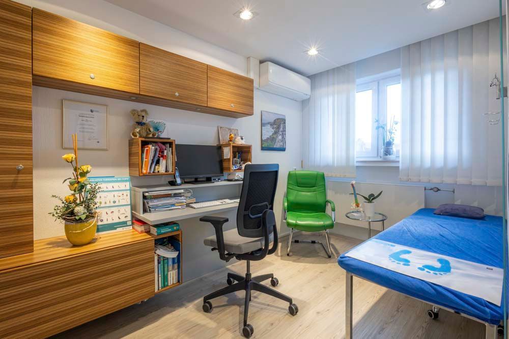 Eine Arztpraxis mit Schreibtisch, Stuhl und Bett.