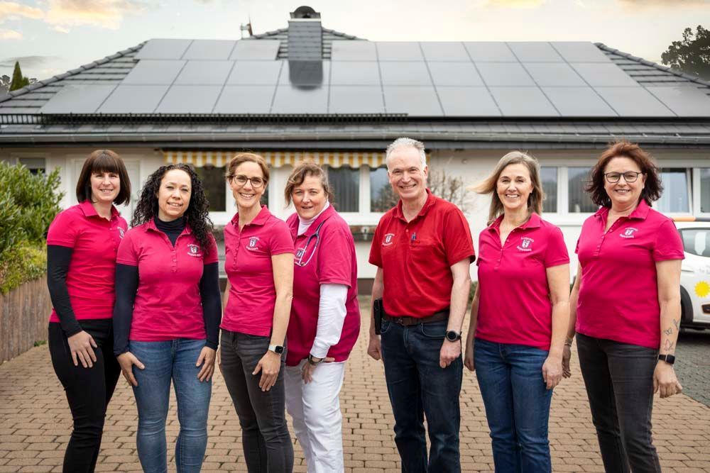 Eine Gruppe von Menschen in rosa Hemden steht vor einem Haus.