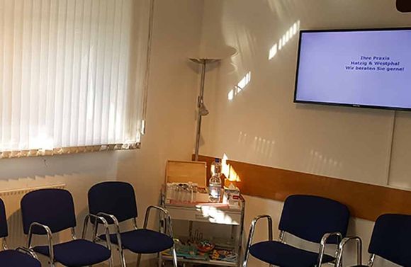 Ein Wartezimmer mit Stühlen und einem Flachbildfernseher.