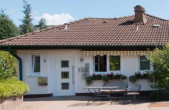 Ein weißes Haus mit einem braunen Dach und einem Tisch und Stühlen davor