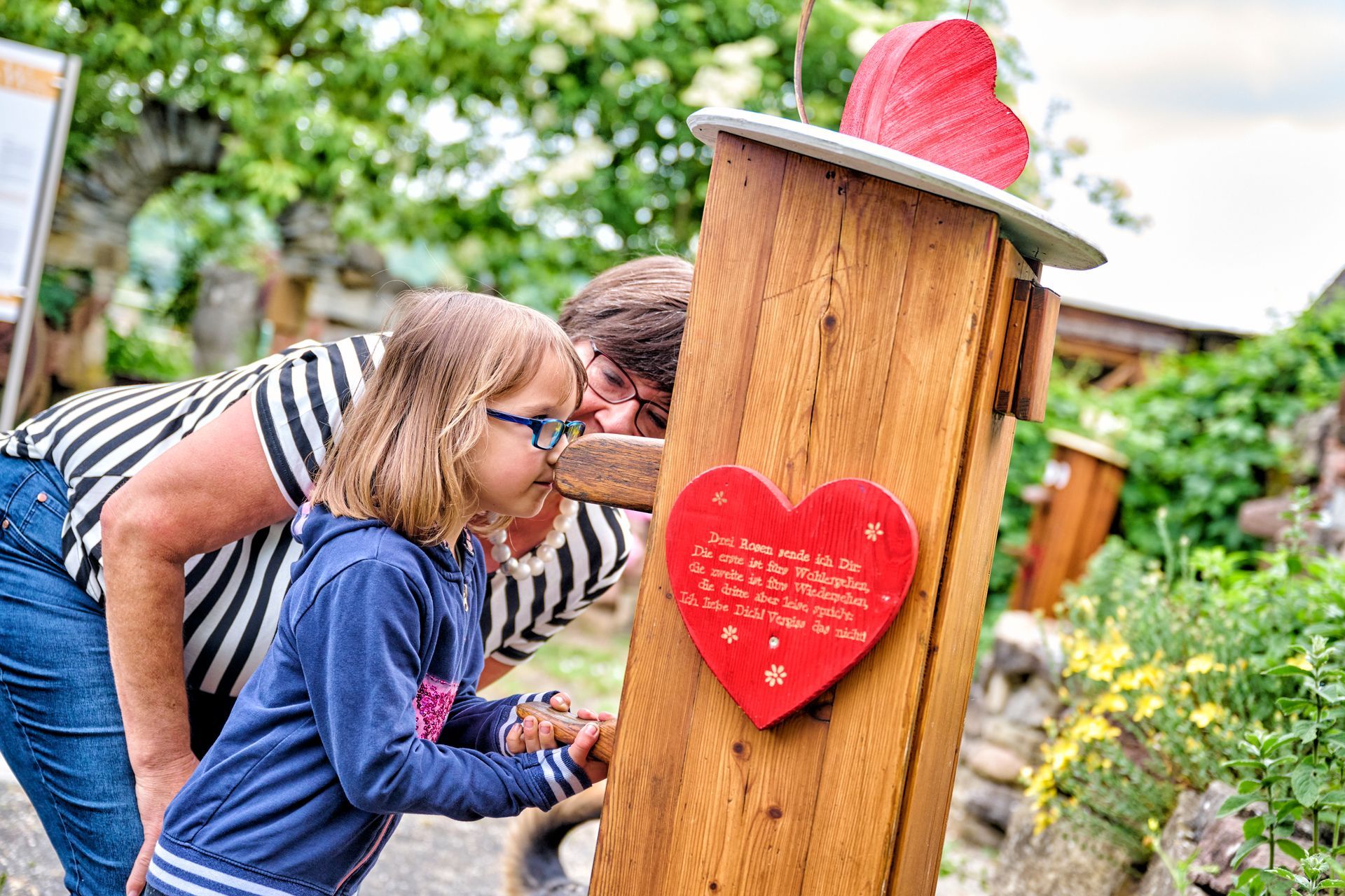 BSI e.V., Elternpaar mit zwei Kindern liest Buch auf einer Wiese