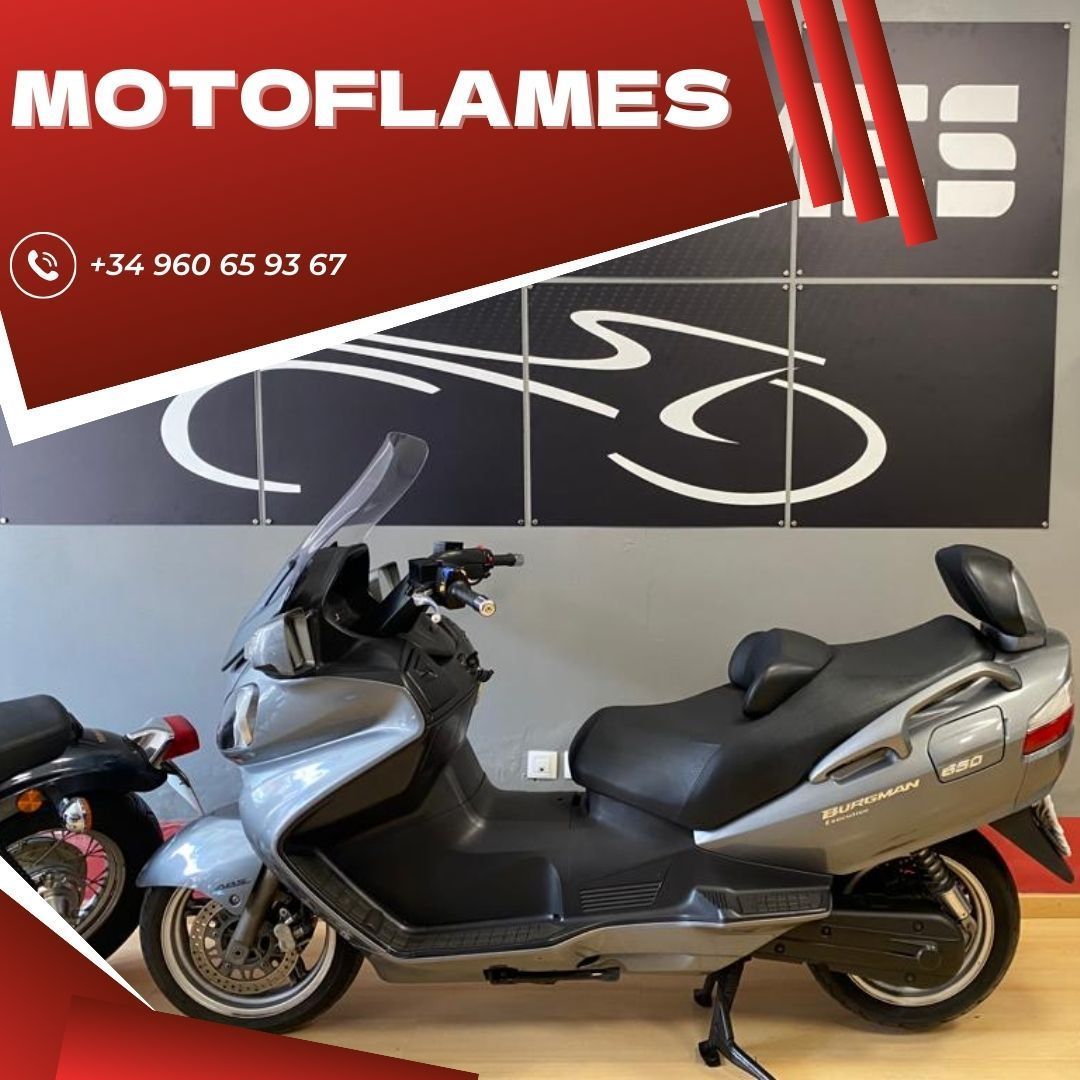 Un scooter está estacionado frente a un cartel que dice motoflames