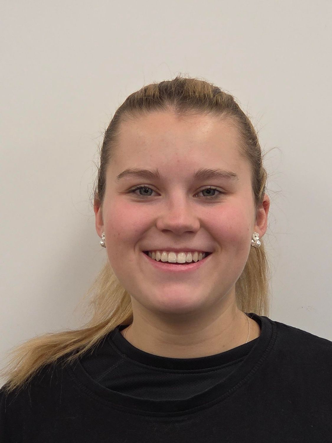 Mann mit lockigem braunem Haar, schwarzem Kapuzenpulli und Ohrpiercings blickt nach vorn.