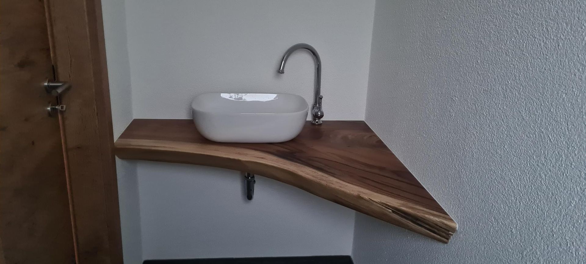 Die offene Holzeingangstür gibt den Blick frei auf ein helles Interieur und einen sonnigen Garten.