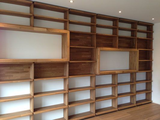 Eingebaute Bücherregale aus Holz mit rechteckigen Ausschnitten an einer weissen Wand.