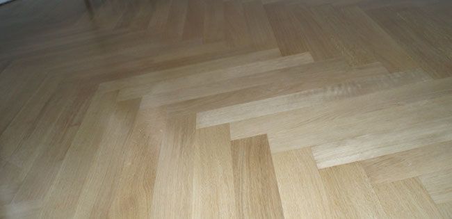 Heller Holzparkettboden im Fischgrätmuster.