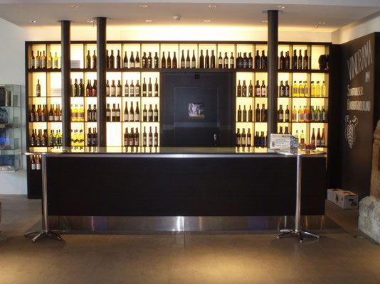 Schwarze Bar mit hinterleuchteten Regalen zur Präsentation von Flaschen; Innenansicht.