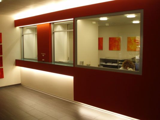 Rote Wand mit Servicefenstern, weissen Akzenten und Innenansicht mit Kunstwerken.