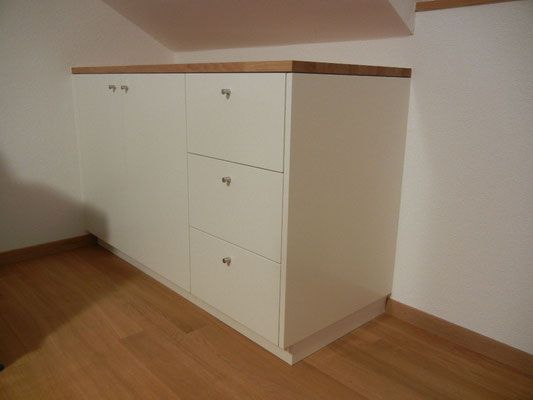Weisser Einbauschrank mit Holzplatte und drei Schubladen. Eckaufstellung mit Holzboden.