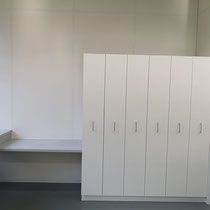 Weiße Schränke und Arbeitsplatte in einem Raum mit weissen Wänden und grauem Boden.