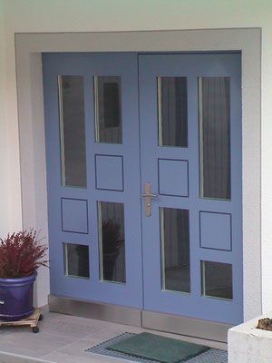 Blaue Doppeltüren mit Glaseinsätzen und silberfarbenen Beschlägen in einem weissen Rahmen.