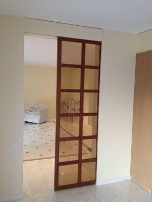 Schiebetür mit Glasscheiben und Holzrahmen. Beige Wände, Marmorboden, Innenraum.