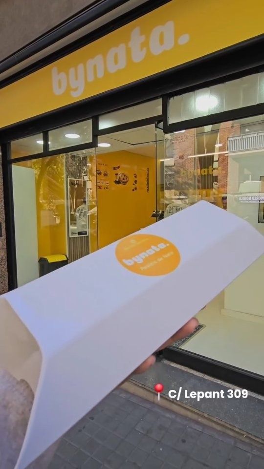 Una persona sostiene un trozo de papel frente a una tienda Bynata.