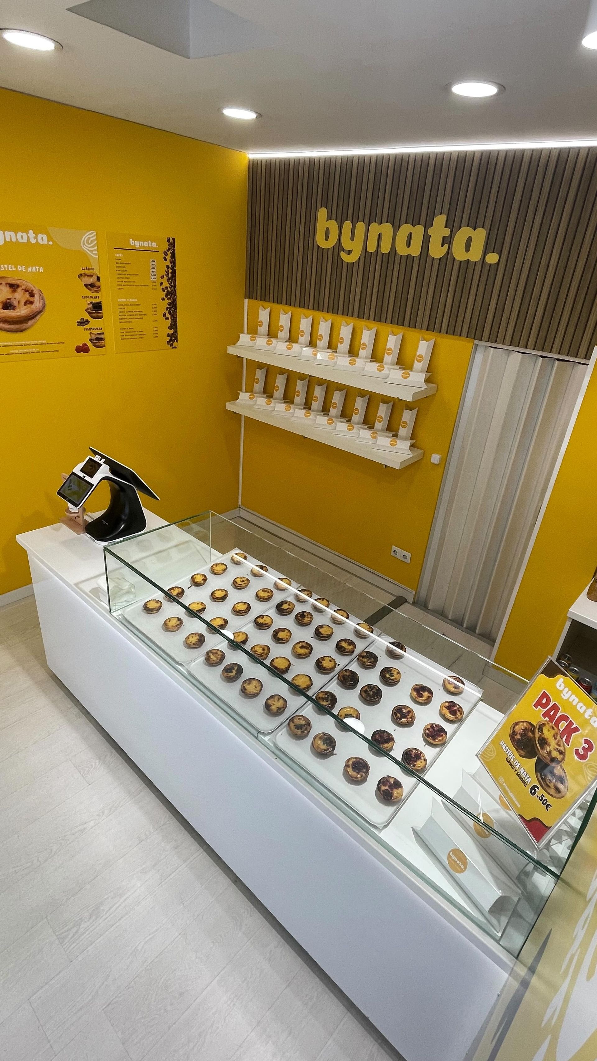 Una panadería con una vitrina llena de donuts y una pared amarilla.