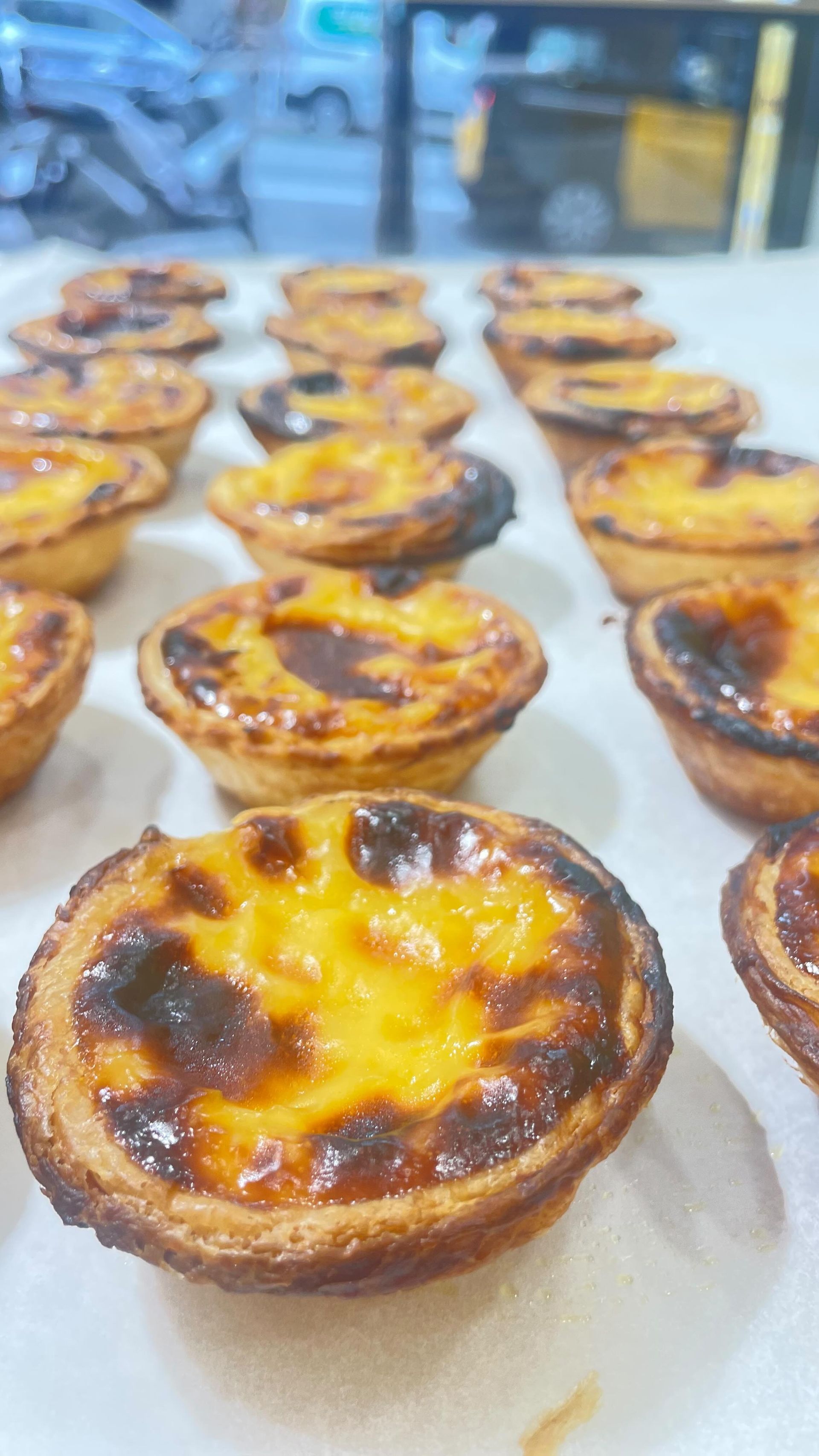 Un montón de tartas de huevo están sobre una mesa.