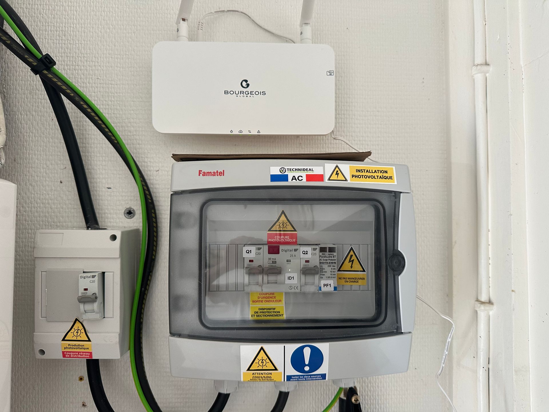 Un tableau électrique et un routeur internet sans fil sont fixés sur un mur blanc avec des panneaux de signalisation de sécurité.