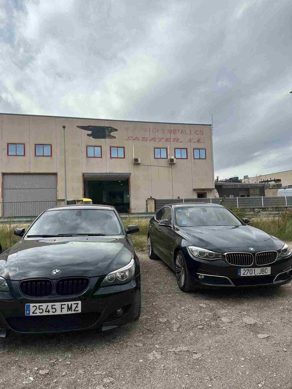Dos coches negros están aparcados delante de un edificio.