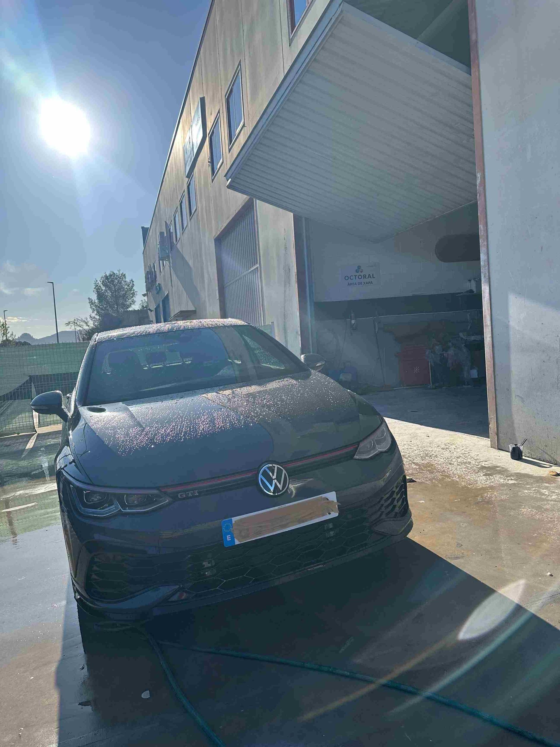 Un coche negro está aparcado delante de un edificio.