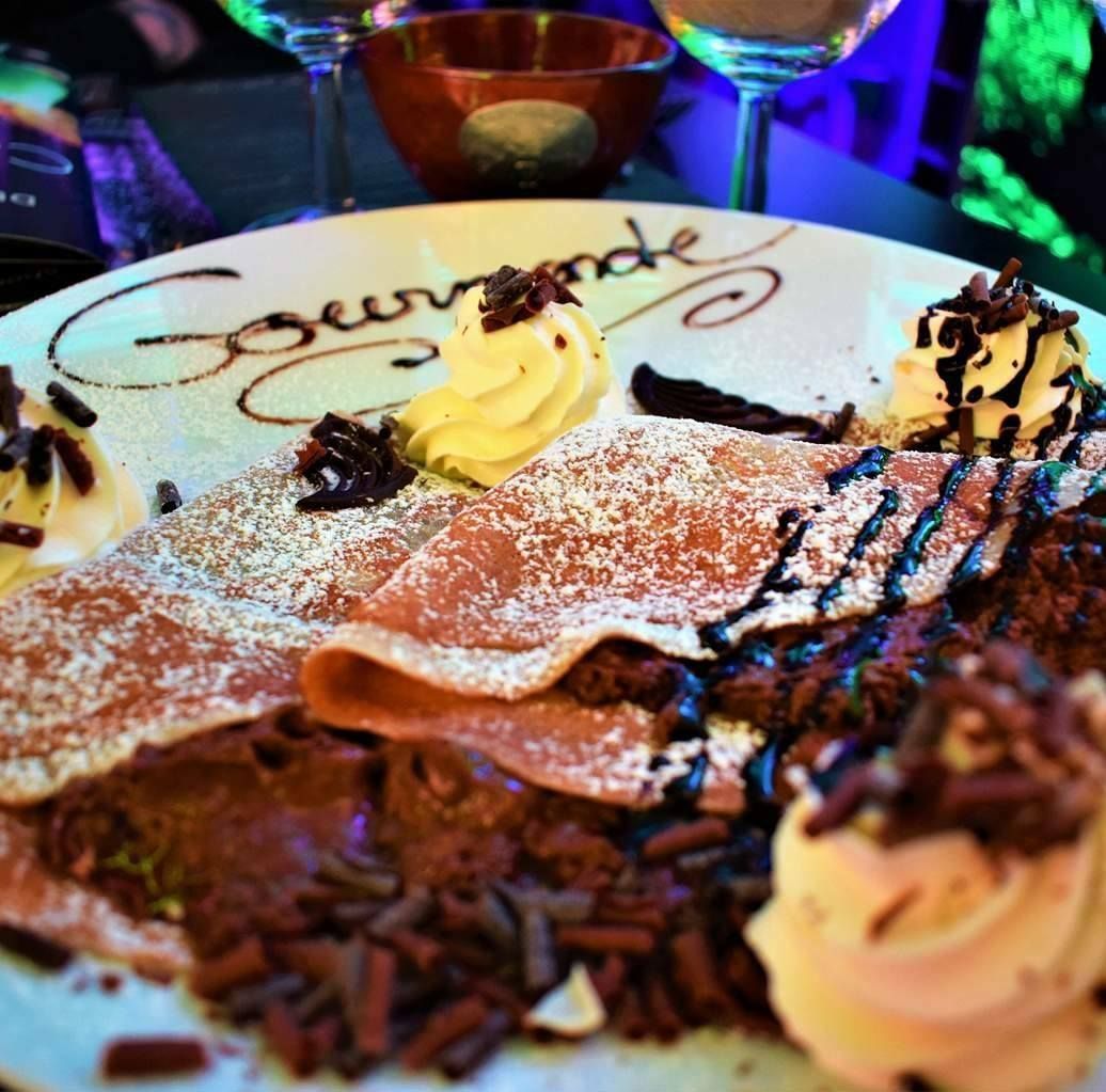 Crêpe sucrée avec du sucre glace et des filets de chocolat dans une assiette